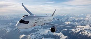 Air Canada airplane flying high in the sky above snow-covered mountains on a clear day.