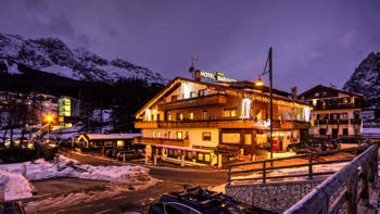 A view of the hotel's exterior at night, showing the snowy mountains and warmly lit building.