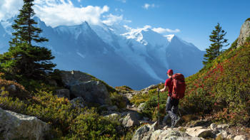 Solo hiker crossing rugged rocky terrain in the Chamonix mountains under a clear sky