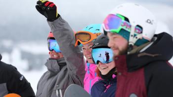A group of skiers in Lapland wearing colorful goggles and winter gear, standing together on a snowy landscape.