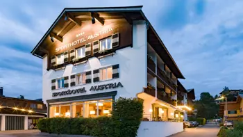 A view of the hotel's exterior, with warm light coming through its windows and clear blue skies above.