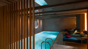 A beautiful indoor swimming pool, with bright blue water and a steamy atmosphere.