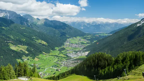 Picturesque alpine village of Neustift, nestled in a green valley with traditional Tyrolean houses and surrounded by towering mountain peaks.