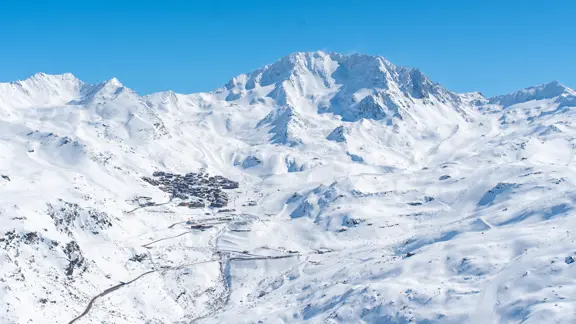 A look of Val Thorens' landscape, with panoramic views of snowy mountains and deep valleys all under a clear blue sky.
