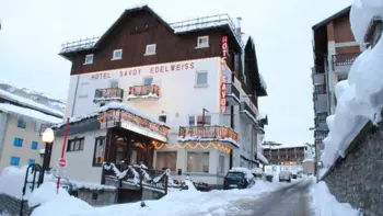 Hotel Savoy Edelweiss in Sestriere, Italy, stands elegantly in the heart of the Milky Way ski area, featuring classic alpine architecture with wood and stone elements