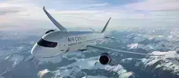 Air Canada airplane flying high in the sky above snow-covered mountains on a clear day.