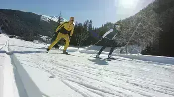 Two skiers swiftly descend a mountain slope, carving through fresh powdered snow.