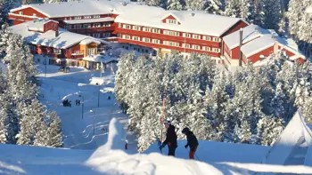 An aerial shot of the hotel's exterior, showing off the vast snowy landscape and forests surrounding its building.