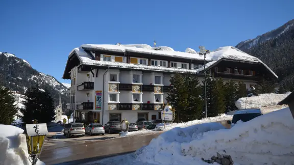 The exterior of Sporthotel Arabba features a charming alpine design with wooden balconies and stone accents