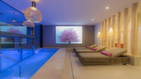 A relaxing spa within the hotel, including lounge chairs and a beautifully lit pool